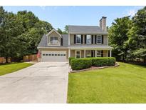 Charming two-story home featuring a well-manicured lawn, two-car garage, and traditional architectural details at 305 Hickory Pointe Ct, Villa Rica, GA 30180