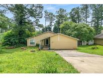 Cozy one-story home featuring a covered porch and driveway amid lush, mature trees at 5016 Comanche Nw Ct, Lilburn, GA 30047