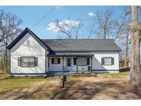 Charming exterior showcasing a freshly painted white home with black trim, a cozy front porch, and landscaped garden at 5119 Ne Worsham St, Covington, GA 30014