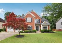 Charming two-story brick home featuring a manicured lawn, mature landscaping, and a three-car garage at 2009 Mclain Nw Rd, Acworth, GA 30101