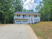 Inviting home with a charming front porch and a two-car garage nestled among mature trees at 294 Spring Leaf Dr, Dallas, GA 30157