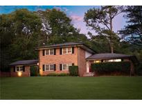 Beautiful two-story brick home with manicured lawn and mature trees providing shade and privacy at 1392 Cornwall Rd, Decatur, GA 30032
