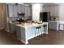 Charming kitchen features gray cabinets, stainless steel appliances, and a large island with bar stool seating at 1783 Shetley Creek Drive, Norcross, GA 30071