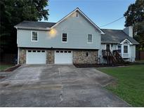 Charming two-story home featuring a light blue exterior, stone accents, a two-car garage, and a well-manicured lawn at 208 Arbour Way, Suwanee, GA 30024