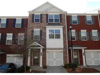 Brick townhome featuring a front-entry garage, white trim, and symmetrical window design at 2199 Landing Walk Dr, Duluth, GA 30097