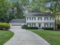Traditional two-story home featuring a lush landscaped lawn, a symmetrical façade, and a long driveway to attached garage at 3609 Meadow Chase Dr, Marietta, GA 30062