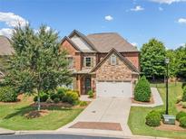 Charming two-story brick home with stone accents, a manicured lawn, and a two-car garage at 3015 Arbor Song Ct, Cumming, GA 30041