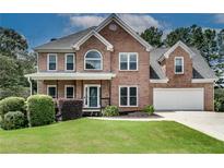 Charming brick home with two-car garage, manicured lawn, and inviting covered front porch at 1226 Kelly Nelson Ct, Lawrenceville, GA 30043