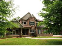 Stunning two-story home featuring a stone and brick facade, complemented by a lush green lawn and mature trees at 2845 Echols Road Rd, Cumming, GA 30041