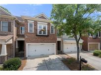 Beautiful brick townhome featuring a two-car garage and lovely front yard landscaping at 6403 Queens Court Trce, Mableton, GA 30126