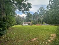 Spacious front yard featuring a home nestled among lush trees, creating a serene and private setting at 241 Wooten Ct, Canton, GA 30114