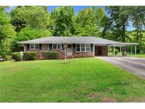 Charming brick home with a well-maintained lawn, mature trees, and a covered carport at 501 Samaritan Dr, Cumming, GA 30040