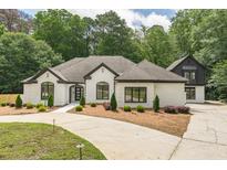 Stunning white brick home with dark trim, manicured lawn, and a circular driveway at 6394 Wood Valley Rd, Douglasville, GA 30134