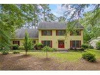 Charming yellow two-story home with red shutters and a well-manicured front yard surrounded by mature trees at 705 Clubhouse Se Dr, Conyers, GA 30094