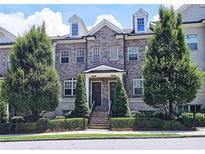 Charming brick townhome with dormer windows, manicured trees, and black metal fencing at 4107 Township Pkwy # 69, Sandy Springs, GA 30342