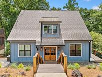 Charming two-story blue home with a wooden entryway and manicured landscaping in a wooded setting at 6900 Driskell Cir, Cumming, GA 30041