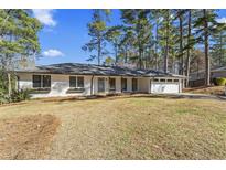 Charming single-story home with a white brick exterior, well-manicured lawn, and an attached two car garage at 4178 Castle Pines Ct, Tucker, GA 30084