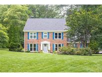 Charming two-story brick home featuring blue shutters, a manicured lawn, and mature landscaping at 1587 Red Fox Sw Run, Lilburn, GA 30047