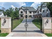 Grand gated entrance with white brick columns and a sweeping drive leading to a luxurious white brick home at 10745 Shallowford Rd, Roswell, GA 30075