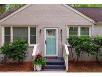 Charming front door with light-blue paint and decorative sidelights, framed by landscaped bushes and dark-painted porch at 2599 E Tupelo Se St, Atlanta, GA 30317