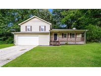 Charming two-story home featuring a covered porch, attached garage, and a well-maintained lawn with green trees at 6194 Golden Meadow Court Ct, Riverdale, GA 30296