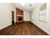 Inviting living room featuring hardwood floors, a brick fireplace, and large windows at 6194 Golden Meadow Court Ct, Riverdale, GA 30296