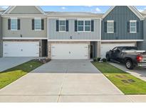 Charming townhome exterior with attached garages and a neatly maintained front lawn in a vibrant community at 11640 Mendenhall Ct, Hampton, GA 30228