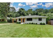 Charming painted brick home featuring a covered parking, front lawn, and mature trees in a peaceful setting at 4237 Rickenbacker Ne Way, Atlanta, GA 30342