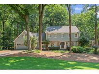 Charming two-story home with a stone facade and attached garage nestled among mature trees at 220 Hollyridge Dr, Roswell, GA 30076