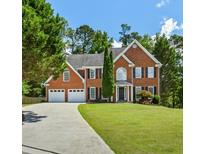 Beautiful two-story brick home with a well-manicured lawn and a long driveway leading to a two-car garage at 2873 Hilton Nw Cir, Kennesaw, GA 30152