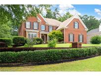 Charming brick home with manicured lawn and mature landscaping featuring black window shutters at 3045 Moss Stone Lane Sw Ln, Marietta, GA 30064