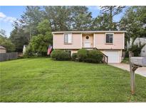 Split-level home boasting a neat lawn, tidy shrubbery and an American flag at 1271 Muirforest Ln, Stone Mountain, GA 30088