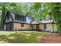 Charming home with a two-car garage, black framed windows, a bright red front door, and verdant landscaping at 6486 Aquila Dr, Morrow, GA 30260