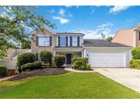 Charming two-story home with a manicured lawn, two-car garage and a mix of brick and siding at 11885 Carriage Park Ln, Duluth, GA 30097