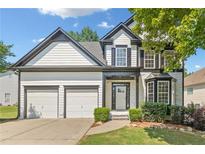 Charming two-story home showcasing a two-car garage, lush landscaping, and a mix of siding and stone finishes at 275 Springs Xing, Canton, GA 30114