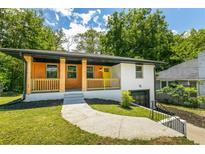 Charming home featuring a blend of wood and painted siding, covered porch, and a bright yellow front door at 1400 North Avenue Nw, Atlanta, GA 30318