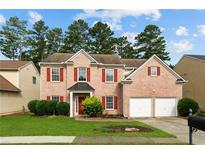Charming two-story brick home with red shutters, lush green lawn, and a two-car garage at 1137 Misty Valley Ct, Lawrenceville, GA 30045