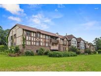Charming condo with brick facade and Tudor-style accents surrounded by a lush green lawn at 124 Camelot Dr, Atlanta, GA 30349