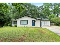 Charming white-brick home with a well-manicured lawn and a bright blue front door at 1694 Pheasant Dr, Atlanta, GA 30238