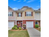 Charming two-story townhome with brick accents, a one-car garage, and lush landscaping in a well-maintained community at 2083 Hasel St, Lawrenceville, GA 30044