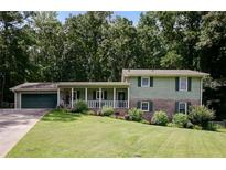 Charming two-story home with a spacious front yard and inviting front porch surrounded by lush trees at 3359 Villa Ln, Douglasville, GA 30135