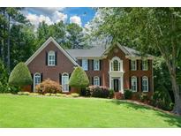 Charming two-story brick home with manicured lawn, mature trees, and inviting front entrance at 1464 Chatsworth Trace, Lawrenceville, GA 30044