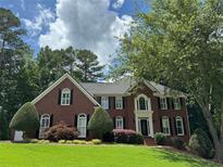 Charming two-story brick home with a well-manicured lawn and mature trees at 1464 Chatsworth Trace, Lawrenceville, GA 30044