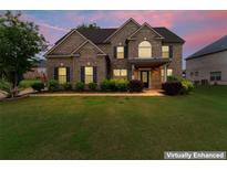 Charming brick two-story home with a well-manicured lawn and inviting curb appeal at twilight at 162 Aylesbury Blvd, Mcdonough, GA 30252