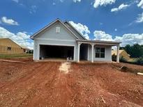 Charming single-story home featuring light blue siding, an attached garage, and inviting covered porch at 2407 Naples St, Hoschton, GA 30548