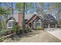 Charming brick home featuring a well-maintained lawn, mature trees, and an attached two-car garage at 2689 Spring Rock Ne Ct, Roswell, GA 30075
