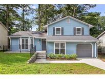 Charming two-story home with light blue siding, gray shutters, attached garage, and well-maintained front lawn at 6176 Hyde Park Ln, Lithonia, GA 30058