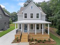 Charming two-story home with gray siding, white trim, inviting front porch, and beautifully landscaped yard at 2214 Meador Ave Se, Atlanta, GA 30315