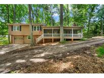 Inviting two-story home featuring a cozy screened porch, attached garage, and surrounded by lush trees at 4323 Japonica Sw Ct, Lilburn, GA 30047