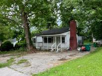 Charming home with a cozy front porch and brick chimney, nestled under mature trees offering shade and curb appeal at 766 Warren Dr, Riverdale, GA 30296